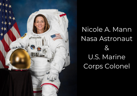 Nicole A. Mann Nasa Astronaut & U.S. Marine Corps Colonel posing in space suit. She is standing in front of a United States flag and holding her helmet.