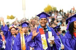 Students in graduation cap and gowns holding their diploma and being excited.