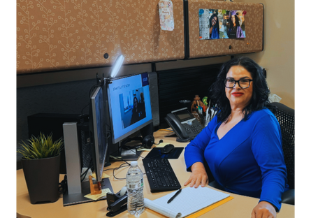 Professor Rachel Revilla poses in front of her computer in her faculty office.