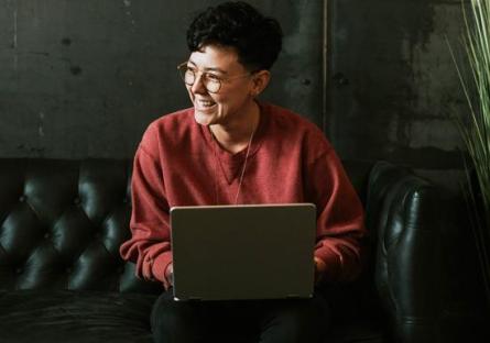 Student on a computer sitting on a couch smiling
