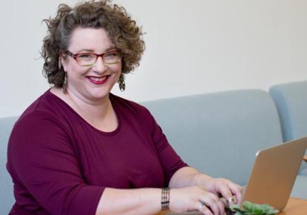 Adult using a laptop and smiling