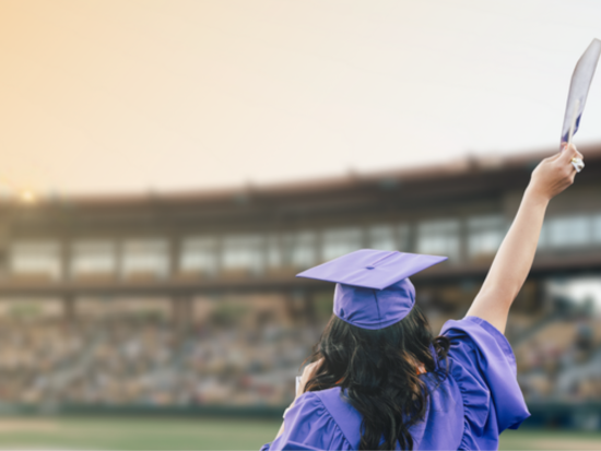 student in graduation regalia holding diploma at graduation ceremony