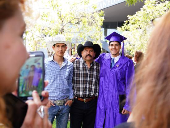 A family posing for a photo with their graduating student