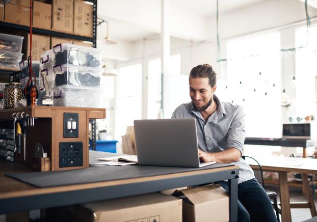 A male student on his laptop while in his home workshop
