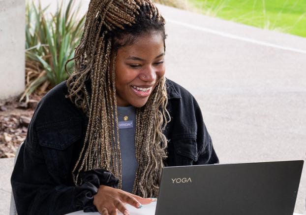 A young african american female student smiles while viewing the her laptop. 