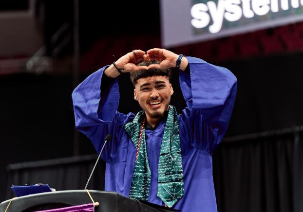 student speaker at graduation ceremony making heart with hands