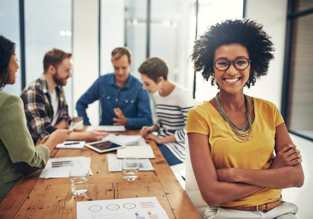 Career person looking at camera as workers working behind them