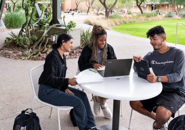 3 students sitting at outside patio on laptops