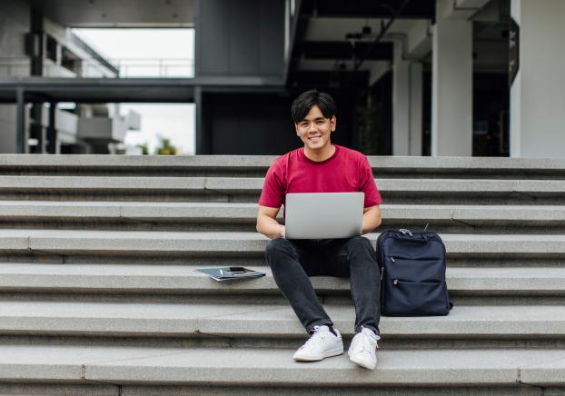 student sitting on stairs working on laptop