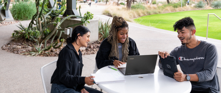 students on the plaza patio looking at a laptop and working together